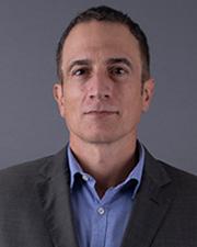 Dr. Acierno wearing a blue shirt and grey blazer against a grey background