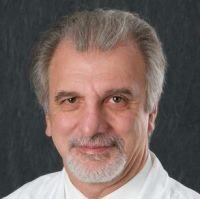 Dr. Jorge wearing a white button down smiling against a grey background