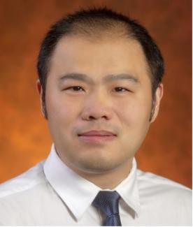 Chao Huang wearing white shirt and black tie with a burnt orange background