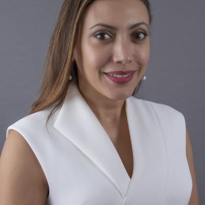 Dr. Hernandez-Tejada smiling wearing a white shirt and grey background